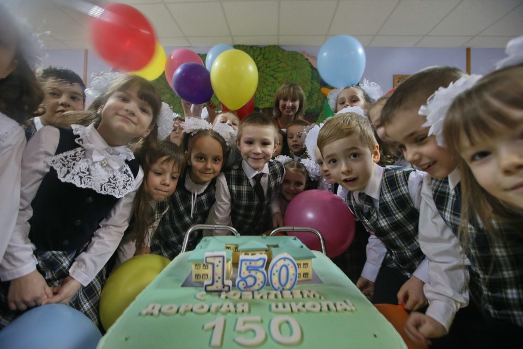 Первоклассники на фоне праздничного юбилейного торта. Фото: Виктор Хабаров