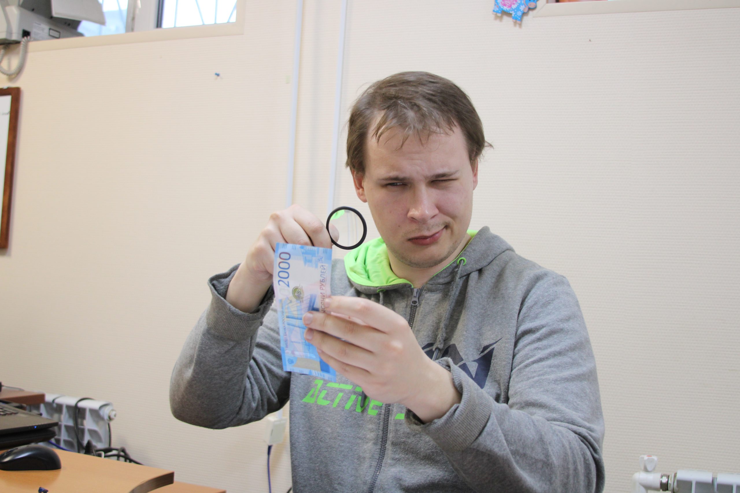 Борис Тебин проверяет купюру на подлинность с помощью лупы